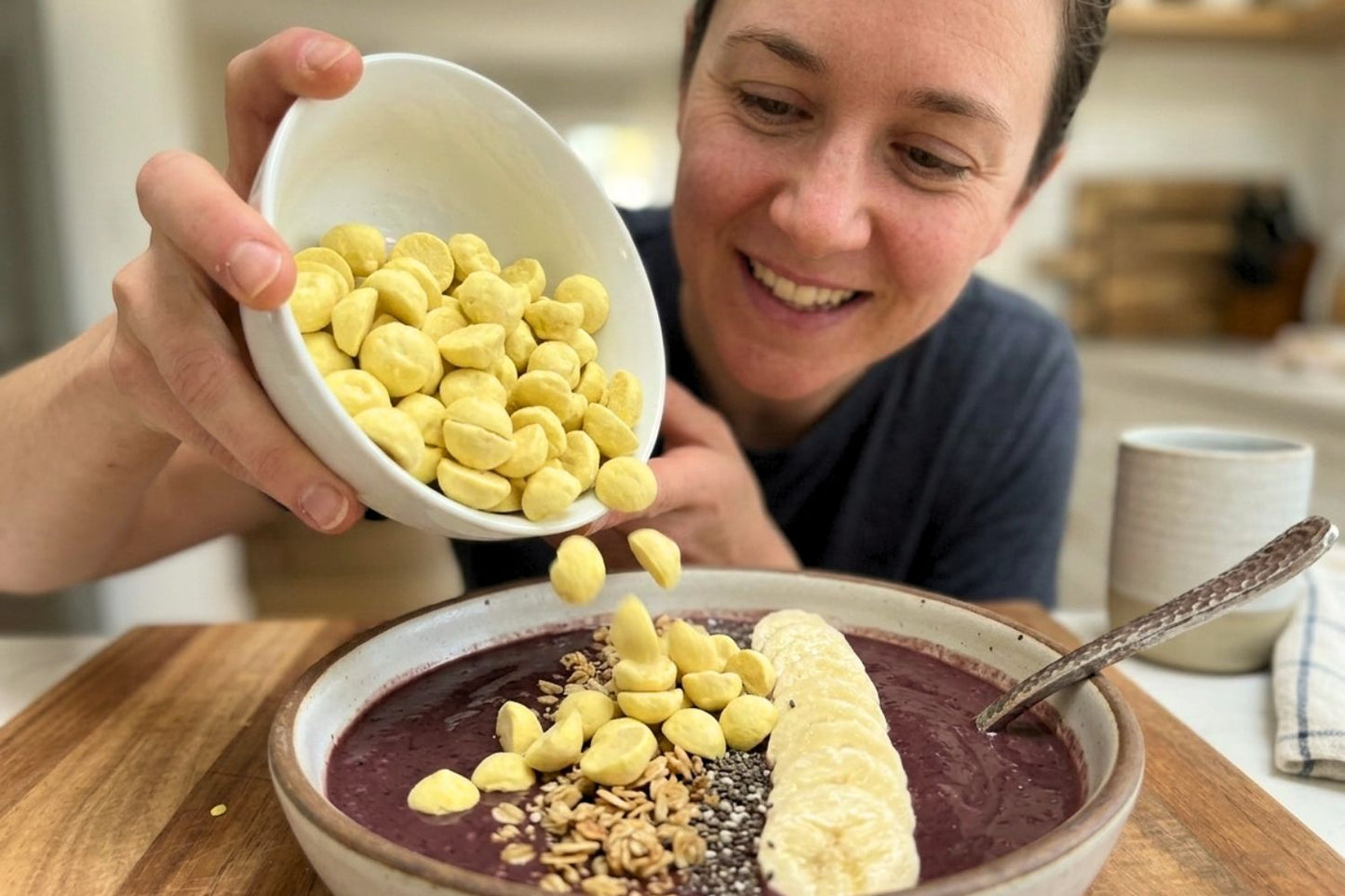Person adding Organic Mango Coconut Smoothie Drops to smoothie bowl